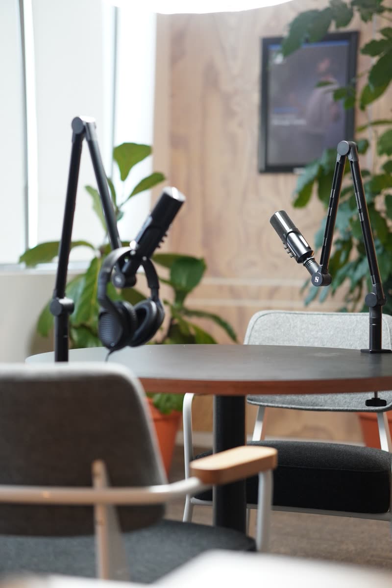 Two microphones on boom arms and headphones at a round table in the WeWork Rosebank podcast studio