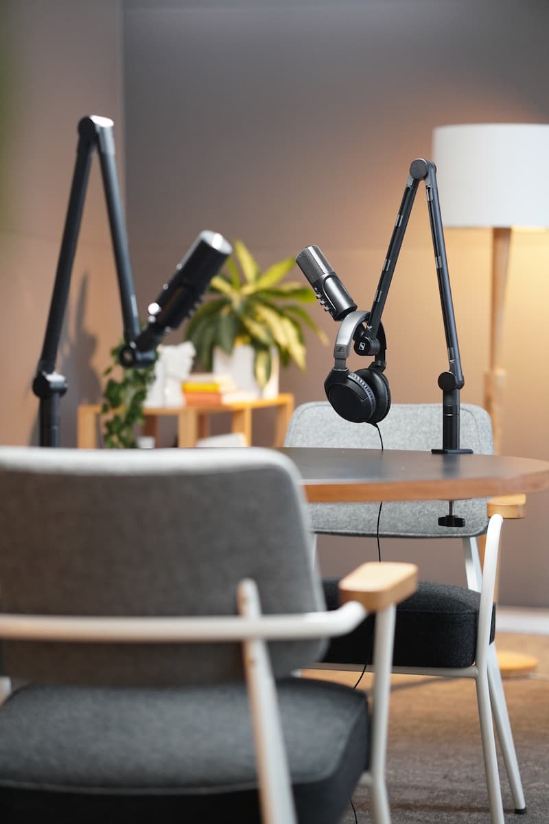 The podcast studio with microphones on boom arms, a floor lamp and a plant